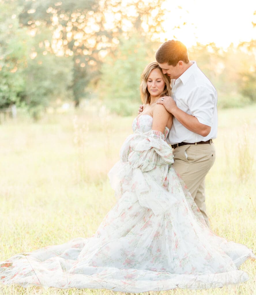 maternity portrait of first time parents with husband behind wife with his hands on her shoulders.