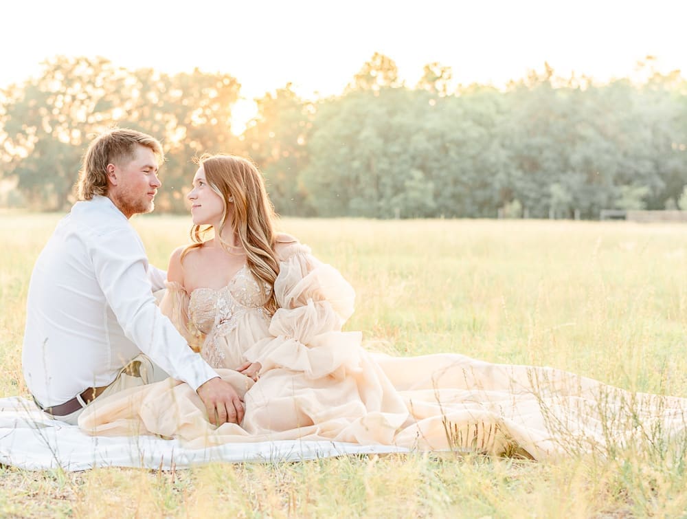 a couple sitting in grass during maternity session