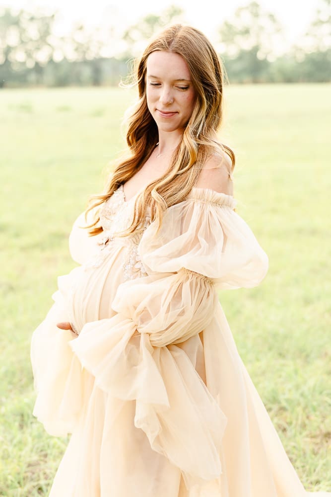 A long cream colored maternity gown with removable long puff sleeves & glittery embellishments on the bust area. Designed by KH Fashions.